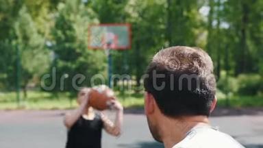 两个运动员在户外球场上打篮球，一个人扔球，另一个人看着他